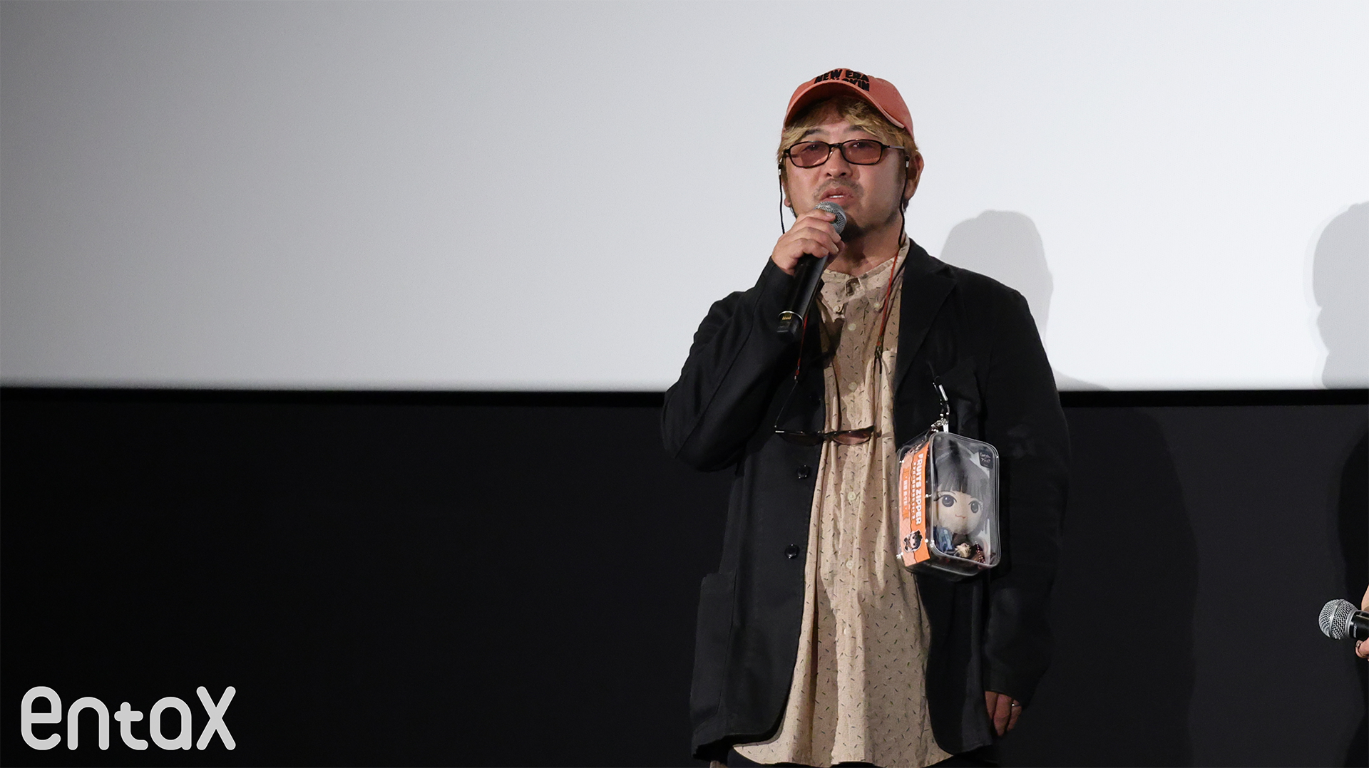 映画のキーアイテム「カセットテープ」を持たせた鎮西のぬいぐるみを身につける清水崇監督