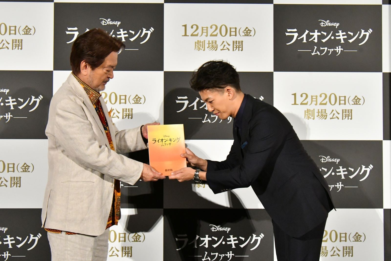 映画『ライオン・キング』30周年舞台あいさつ ムファサ王の吹替声優を務めた⼤和⽥伸也(左)から、最新作で若き日の“ムファサ”の声優を演じる尾上右近(右)にバトン代わりに台本とぬいぐるみが渡された